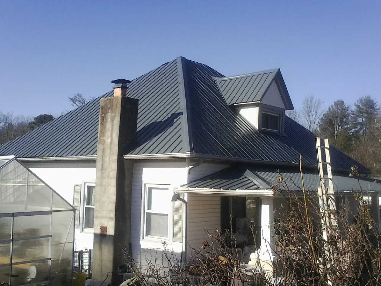 Dark blue standing seam metal roof on a white farmhouse with dormer — Slate & Tile Roof Repair by Roofing Brothers in Virginia