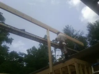 Carpenter setting a ridge beam over a new addition frame — Ice Dam Removal by Roofing Brothers in Virginia