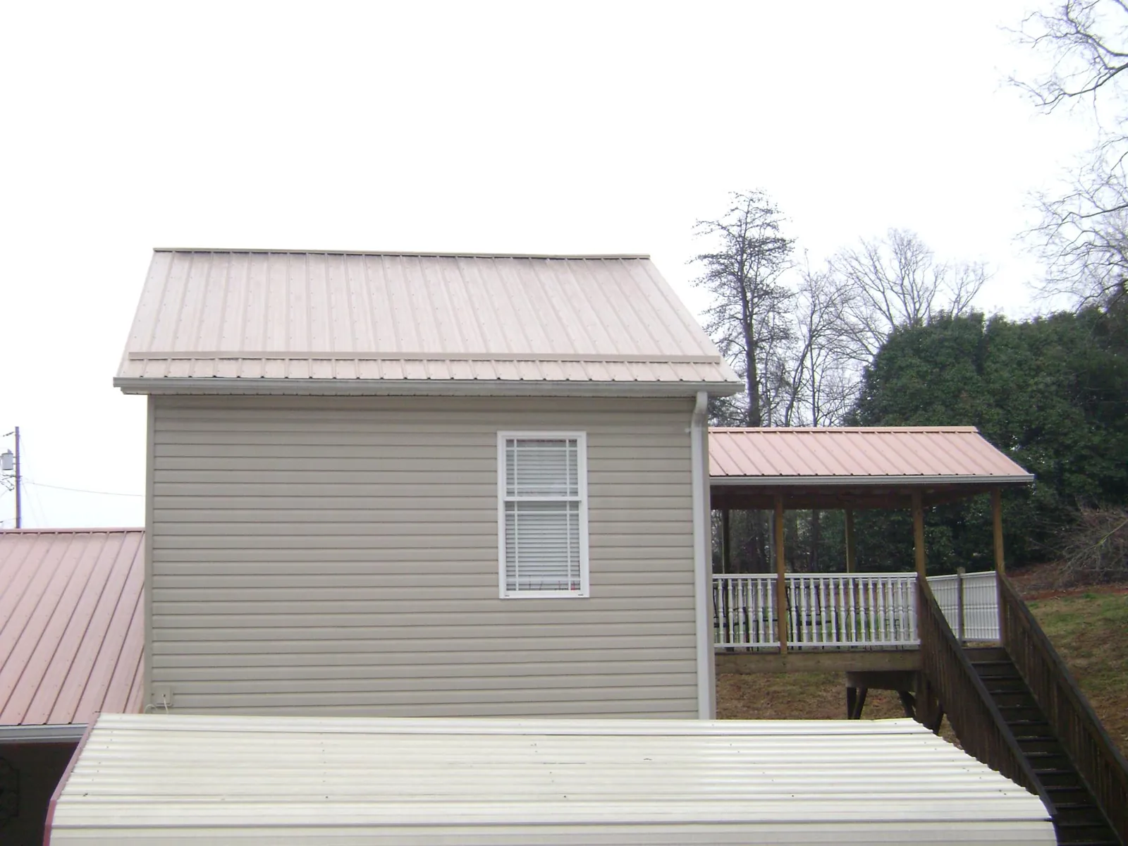 Tan metal roofs on a two story addition and attached porch, from a Roof Replacement job in Virginia